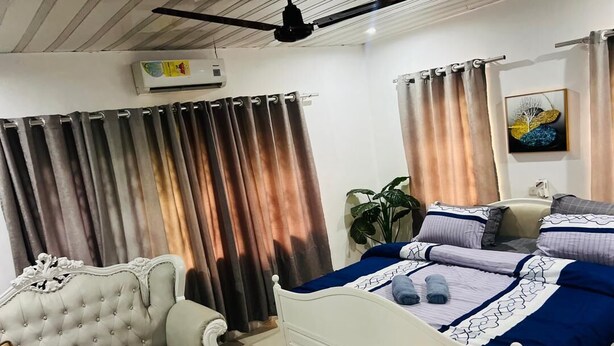 Un dormitorio con una cama, un sofá blanco, un ventilador de techo y cortinas.