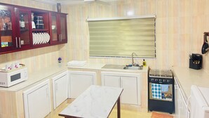 Una cocina compacta con microondas, estufa y armarios.