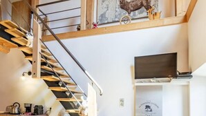 A modern interior with a wooden staircase, a mounted television, and a framed artwork of a deer. - The Bear Fountain (LA FECLAZ LES DESERTS)
