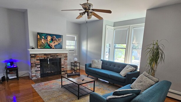 A living room with a fireplace, a blue sofa, a coffee table, and a ceiling fan.