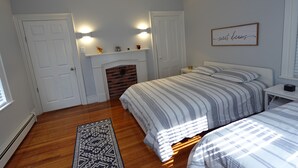 A bedroom with two beds, a fireplace, and a wall-mounted sign.