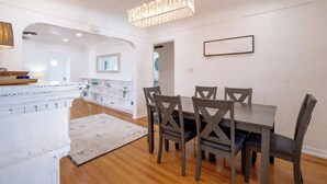 A dining area with a rectangular table and four chairs, a chandelier, and a white wall with a framed quote. - Charming 2-bedroom house, Downtown Flagstaff with AC (Flagstaff)
