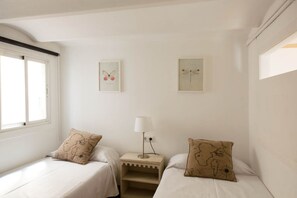 Een kamer met twee bedden, een nachtkastje, een lamp en twee foto’s aan de muur.