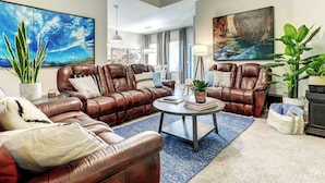 Ein geräumiges Wohnzimmer mit Ledersofas, einem Couchtisch und großformatiger Wandkunst.