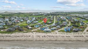 Vista aérea de una zona residencial costera con casas, una playa y una masa de agua.