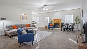 A spacious living room with a gray sofa, blue armchair, and a fireplace.