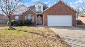 A two-story house with a garage, a front yard with a tree, and a clear sky.