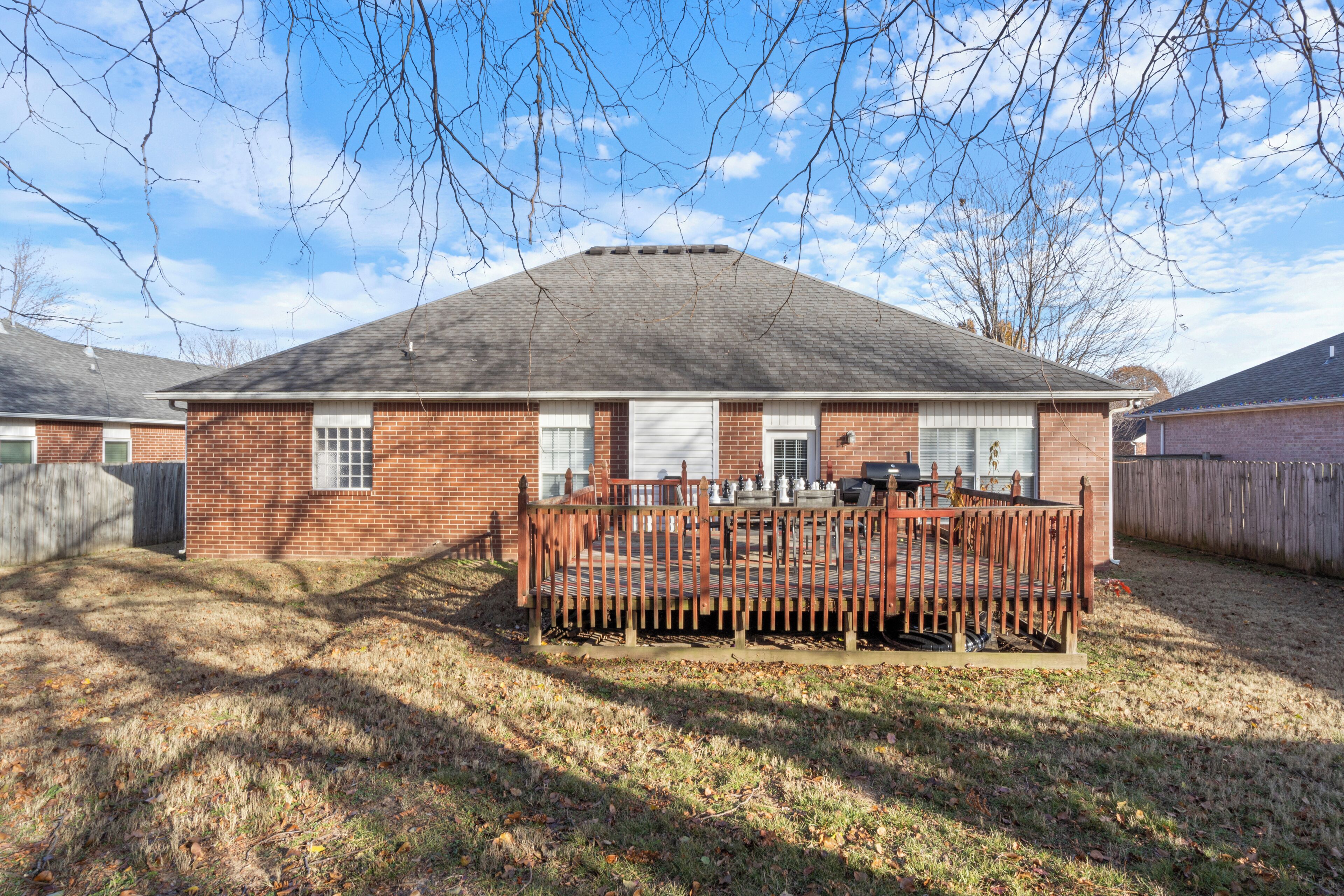 A single-story brick house with a fenced deck and a garage.