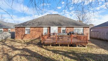 A single-story brick house with a fenced deck and a garage.