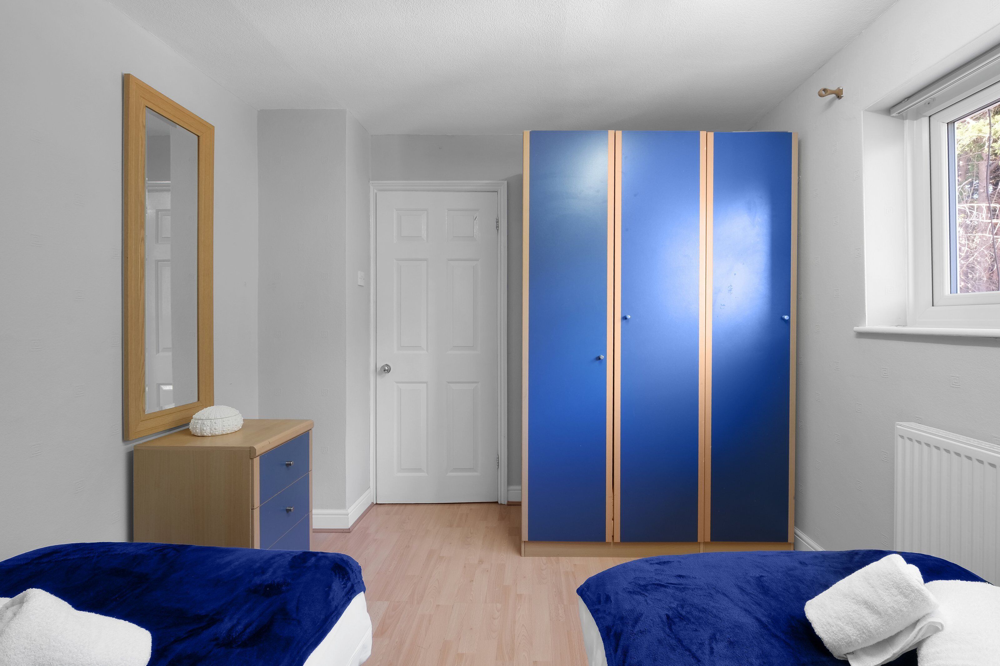 Quarto com guarda-roupa, espelho e janela.
