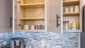 A kitchen with a coffee machine, a potted plant, and various kitchen items on the counter. - Hot Tub w Mountain View Pets OK (Westminster)