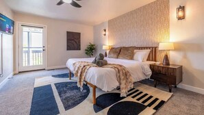 A bedroom with a bed, two bedside tables, a ceiling fan, a patterned wall, and a door leading outside. - Hot Tub w Mountain View Pets OK (Westminster)