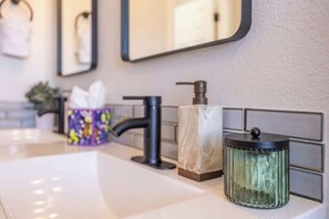 A bathroom with a white sink, a black faucet, a soap dispenser, and a glass container with a black lid. - Hot Tub w Mountain View Pets OK (Westminster)