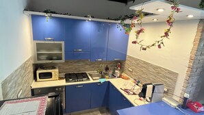A compact kitchen with blue cabinets, a microwave, a gas stove, and a sink. - Shelter among olive trees, Tuscan countryside, a stone's throw from characteristic cities (Toscana)