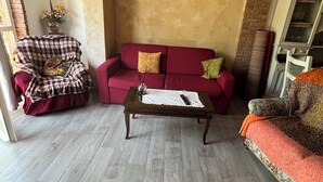 A cozy living room with a red sofa, a plaid-covered chair, and a wooden coffee table. - Shelter among olive trees, Tuscan countryside, a stone's throw from characteristic cities (Toscana)