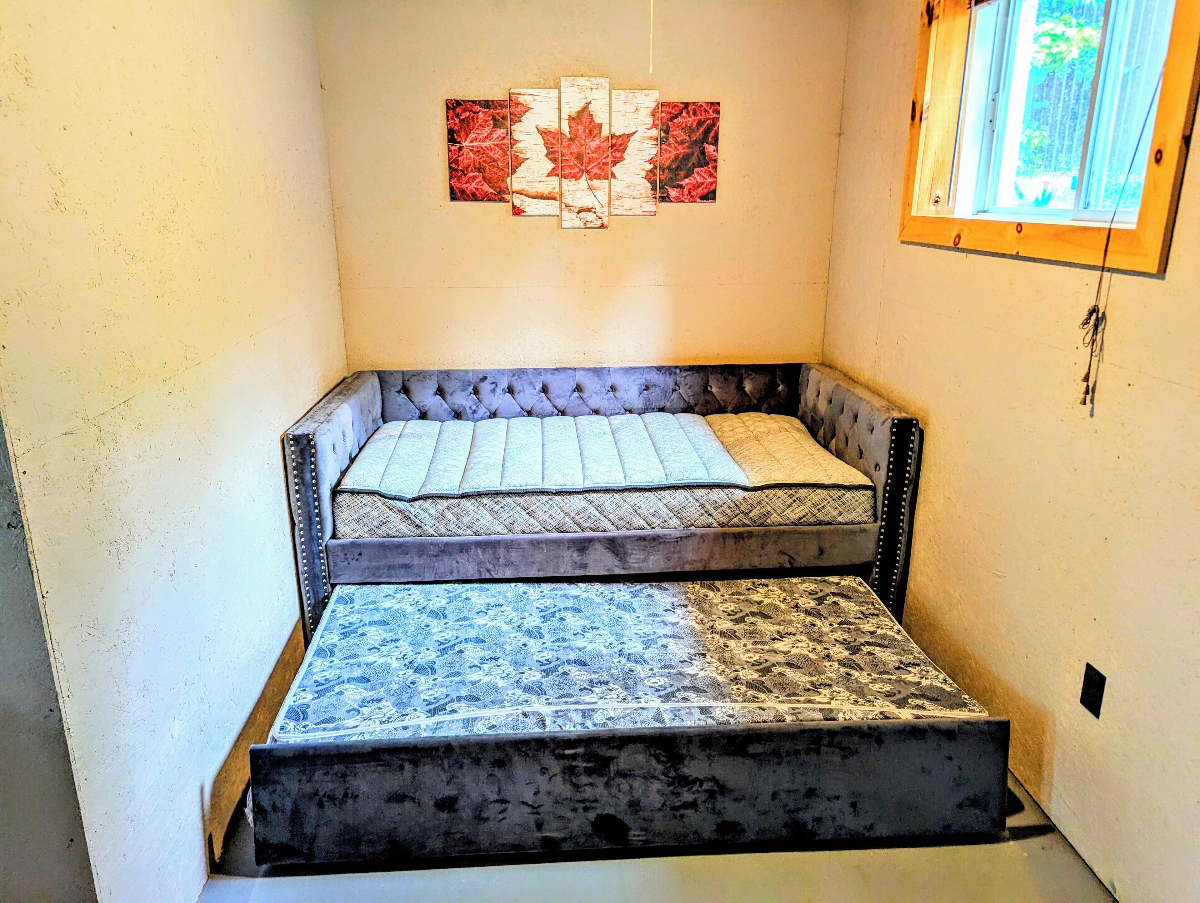 Une petite pièce étroite, avec un lit et une fenêtre.