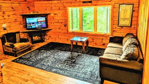 A log cabin interior with a television, a sofa, a coffee table, and a rug. - Beautiful Log Home + XL BUNKIE by Weslmkoon lake (Denbigh)