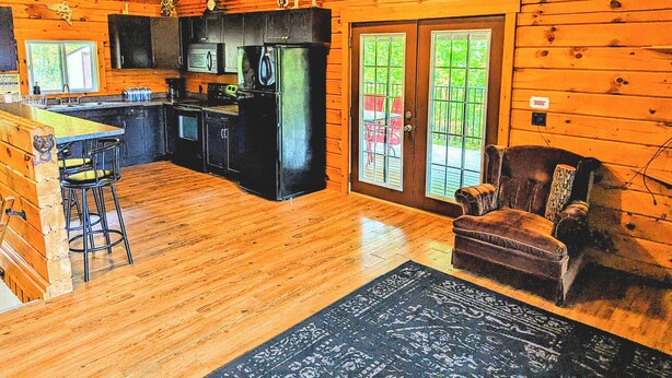 A log cabin interior with a kitchen, dining area, and a cozy seating area. - Beautiful Log Home + XL BUNKIE by Weslmkoon lake (Denbigh)