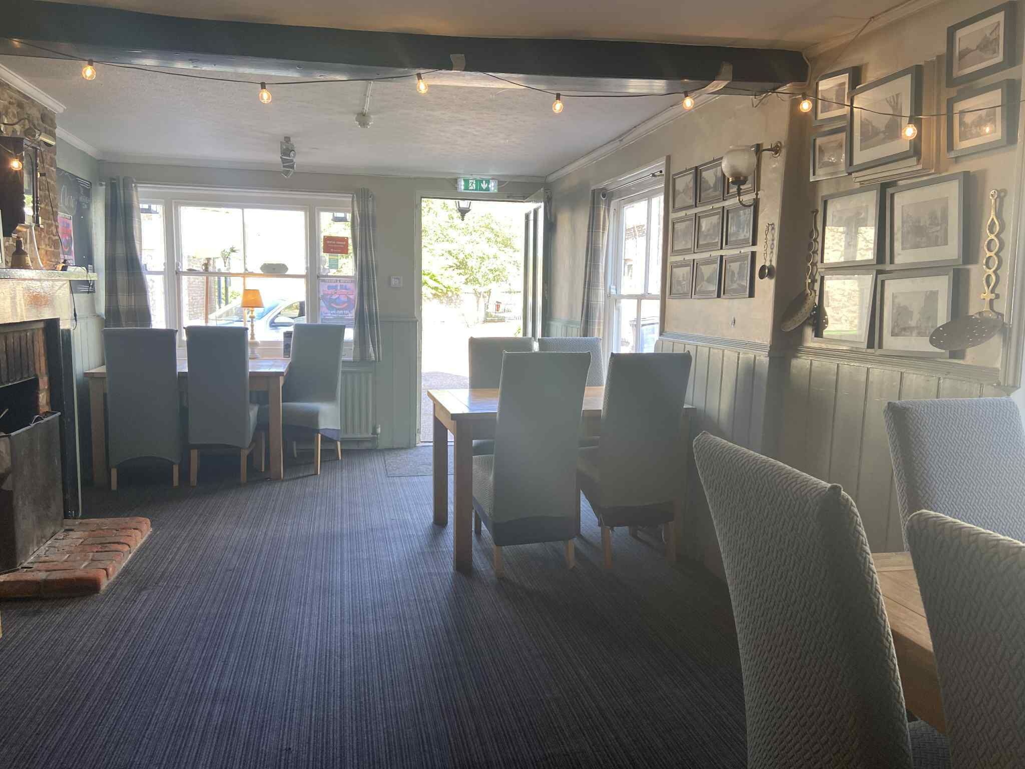 A cozy restaurant with a brick fireplace, wooden tables, and chairs.
