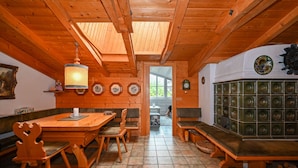 A wooden interior with a dining table, benches, and a clock on the wall.