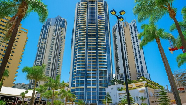 A tall, modern hotel with a curved facade, surrounded by palm trees and other buildings. - Ocean View Rental Surfers Paradise (Surfers Paradise)