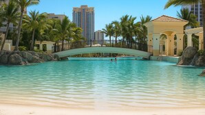 A pool area with a bridge, palm trees, and a beach. - Ocean View Rental Surfers Paradise (Surfers Paradise)
