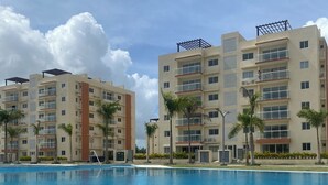 Una piscina con vistas a edificios altos, palmeras y un cielo despejado.