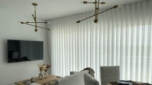 Una sala moderna con un sofá, una mesa de comedor con platos y un televisor montado en la pared.