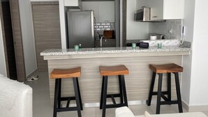 Una cocina moderna con encimera de granito, electrodomésticos de acero inoxidable y taburetes de madera.