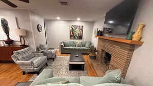 A living room with a fireplace, two sofas, a coffee table, and a TV mounted on the wall.