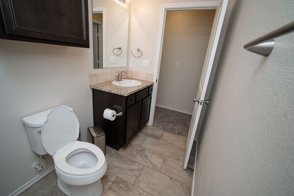 A compact bathroom with a toilet, sink, and dark cabinetry.