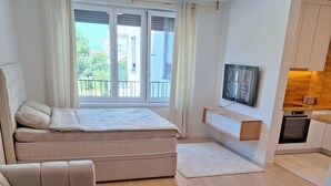 A modern apartment with a sofa, a bed, a TV, and a kitchenette. - Sunset Dream Apartment (Sarajevo)