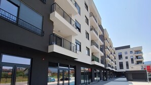 A modern multi-story building with balconies, large windows, and a paved walkway. - Sunset Dream Apartment (Sarajevo)