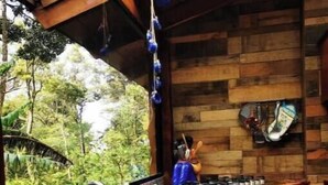 A kitchen with a sink, stove, and hanging utensils.