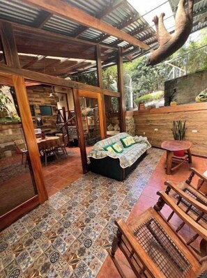 Una habitación amplia con suelo estampado, muebles de madera y una cama grande con una manta verde.