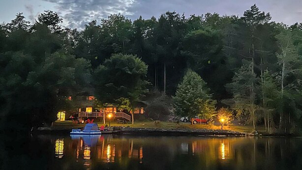A lakeside cabin with a dock, surrounded by dense forest.