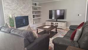 A modern living room with a fireplace, a flat-screen TV, and a sofa.