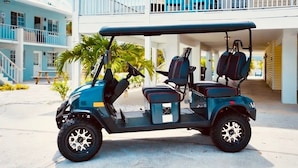 Une voiturette de golf est garée devant un immeuble doté d’un balcon.