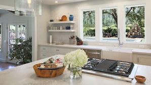 Una cocina moderna con una isla central, estufa integrada y una ventana con vistas al exterior.