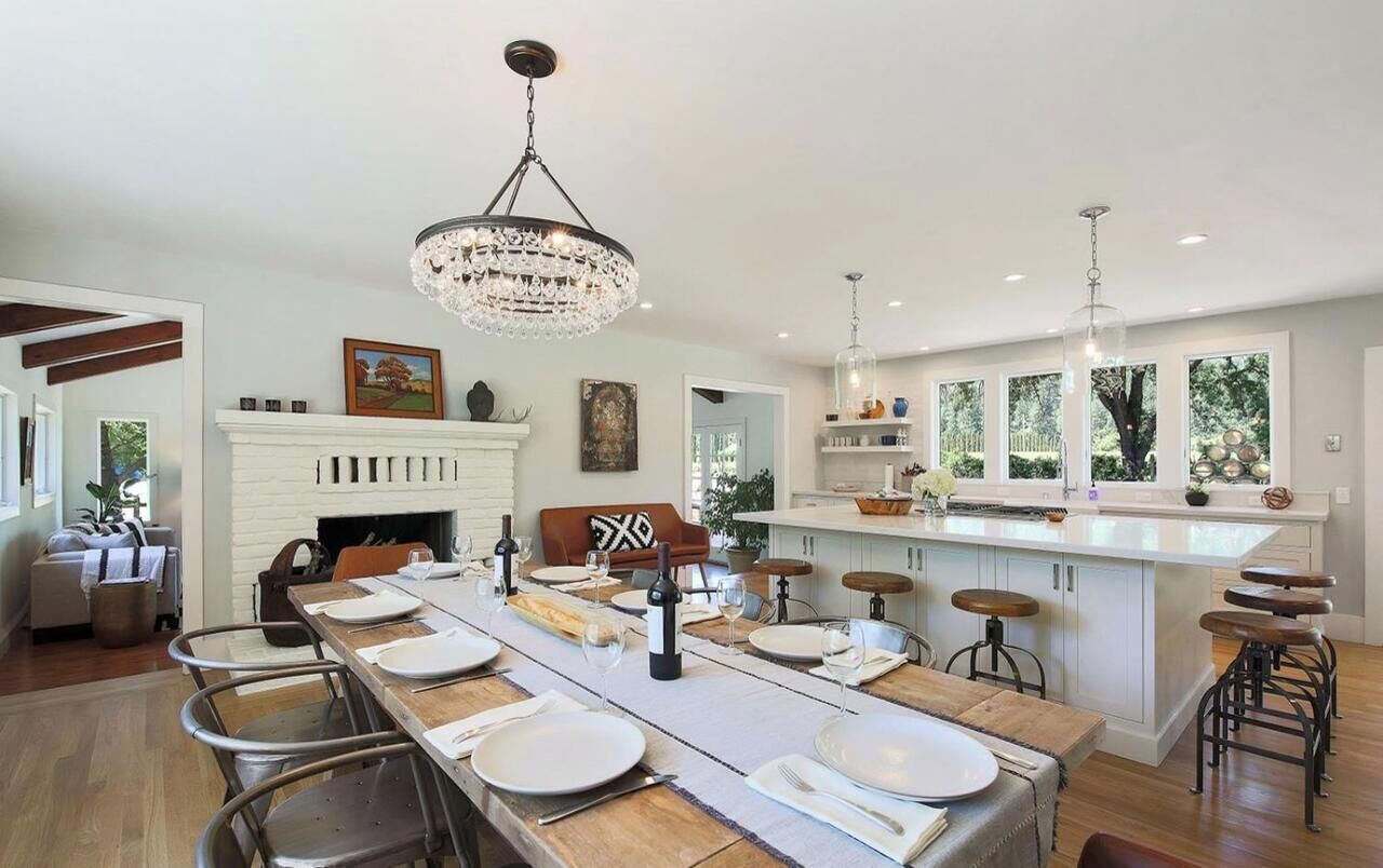 Cozinha espaçosa com uma mesa de jantar comprida, armários brancos e lareira.