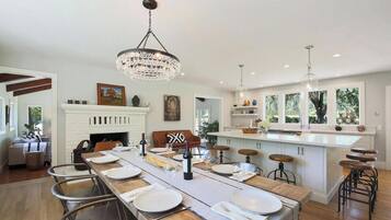 Cozinha espaçosa com uma mesa de jantar comprida, armários brancos e lareira.