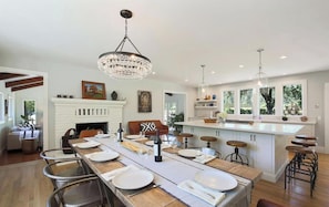 A spacious kitchen with a long dining table, white cabinetry, and a fireplace.