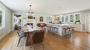 Una cocina amplia con una isla central, taburetes de bar e iluminación colgante.