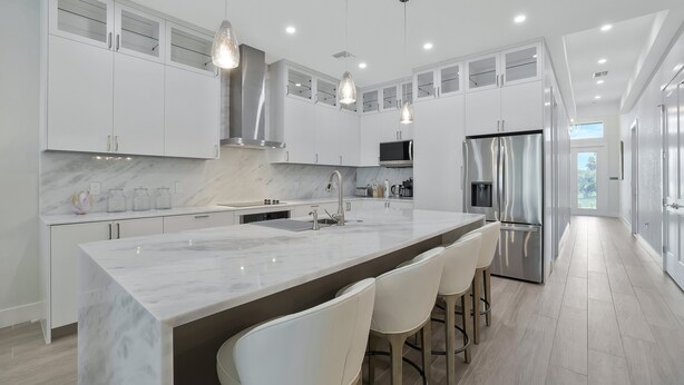A modern kitchen with white cabinetry, a marble island, stainless steel appliances, and pendant lighting. - New! Sunset Walk – Brand New Luxury Home, Just a Short Stroll to Vanderbilt Beach (Naples)