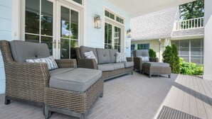 A covered outdoor seating area with wicker furniture and a grey sofa. - NEW Lakeside Cottage Sleeps 16 Includes Golf Cart Walk to Lake and Near Pool (Lakeside)
