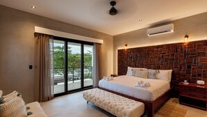 A bedroom with a large bed, a sofa, a wooden headboard, and a view of the outdoors. - Luxury Beachfront Villa! Newest Home in Jaco! (Jaco)