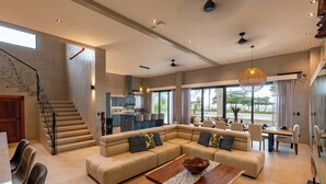 A spacious living area with a large L-shaped sectional sofa, a wooden coffee table, and a dining area with a table and chairs. - Luxury Beachfront Villa! Newest Home in Jaco! (Jaco)