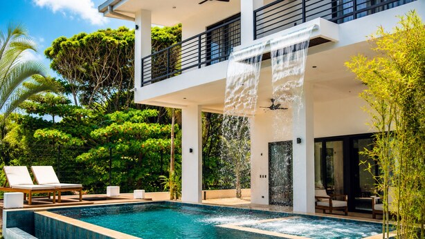 A modern house with a swimming pool, outdoor seating, and a waterfall feature. - Luxury Beachfront Villa! Newest Home in Jaco! (Jaco)