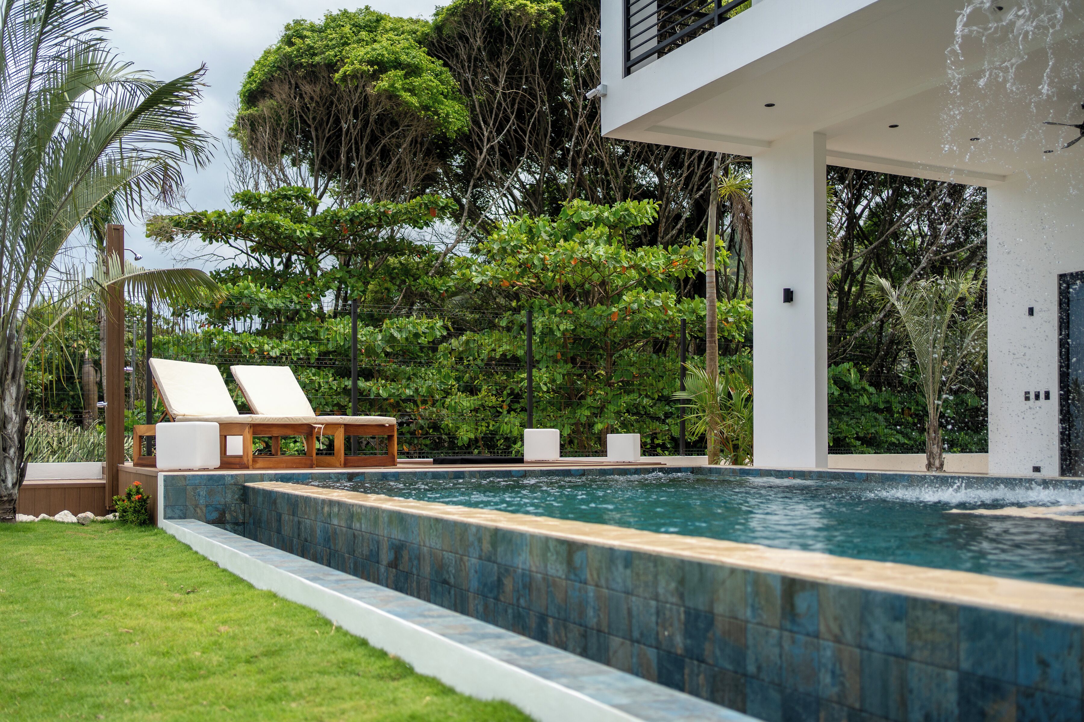 A modern pool area with lounge chairs and a clear view of the surrounding lush greenery.