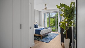 A bedroom with a bed, a ceiling fan, a large window, and a potted plant. - PFR Suites - Butler|2-Story Lawrenceville Penthouse w/ Rooftop Terrace|2 King Beds /2.5 Bath|Parking (Pittsburgh)